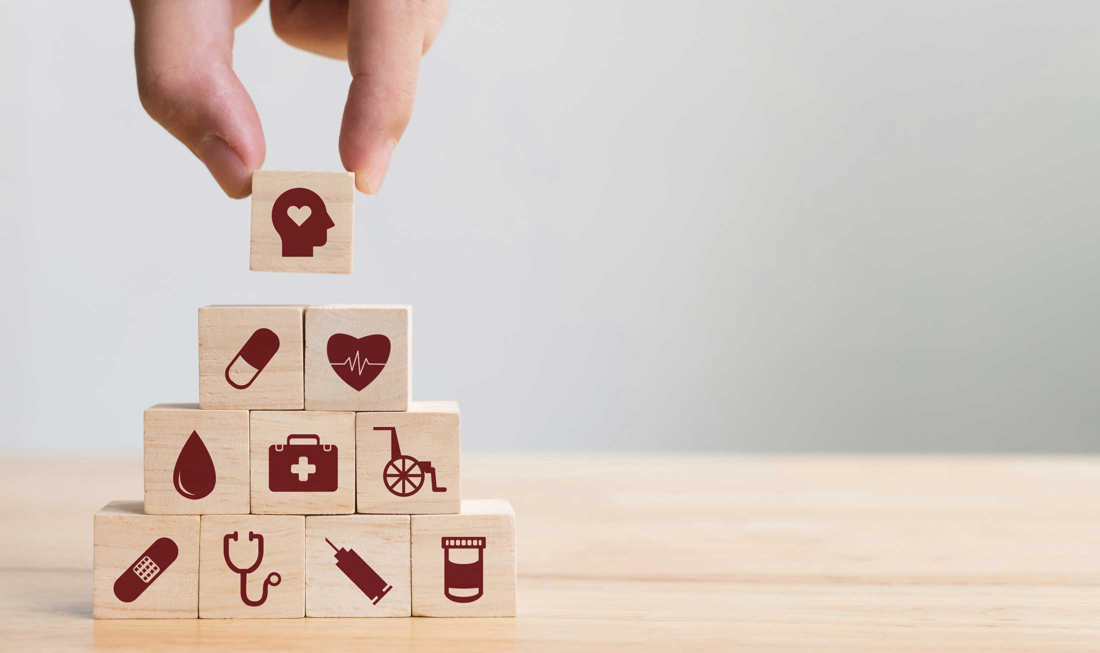fingers stacking small building blocks with health related logos on them